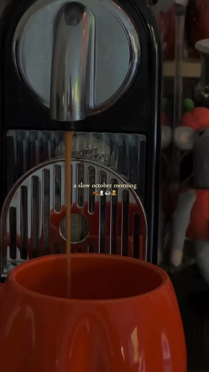 A frame of the original video: espresso pouring into an orange cup, captioned “a slow october morning”